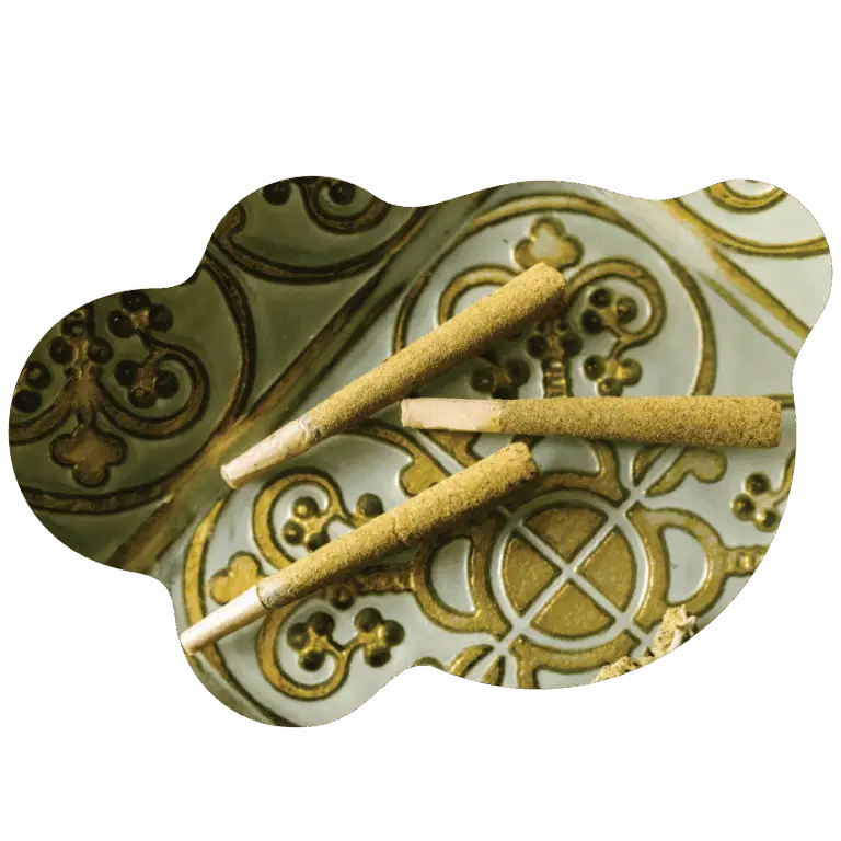 Three cannabis pre-rolls coated in kief resting on an ornate green and gold tray, representing premium offerings from Housing Works Cannabis Co.
