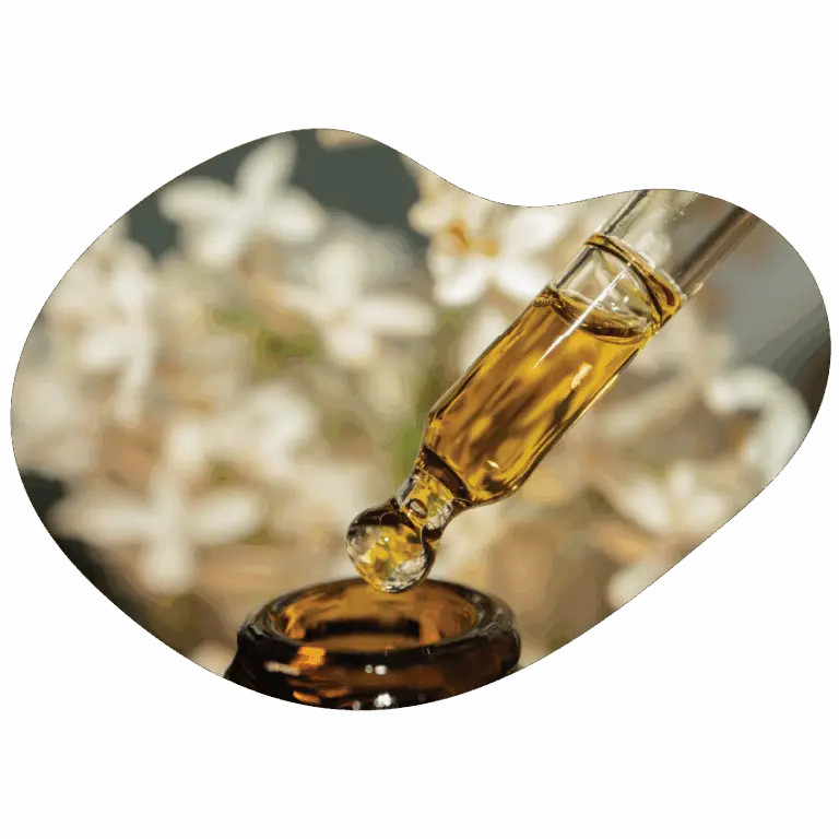 Dropper releasing golden cannabis tincture into a small amber bottle, with soft floral background highlighting Housing Works Cannabis Co. tincture products.