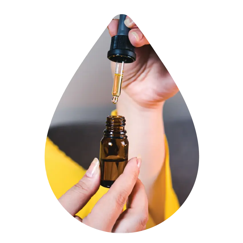 Close-up of a person using a dropper to dispense cannabis tincture from a small amber bottle, representing Housing Works Cannabis Co. tincture products.