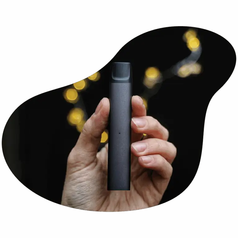 Hand holding a sleek black cannabis vape pen with blurred string lights in the background.
