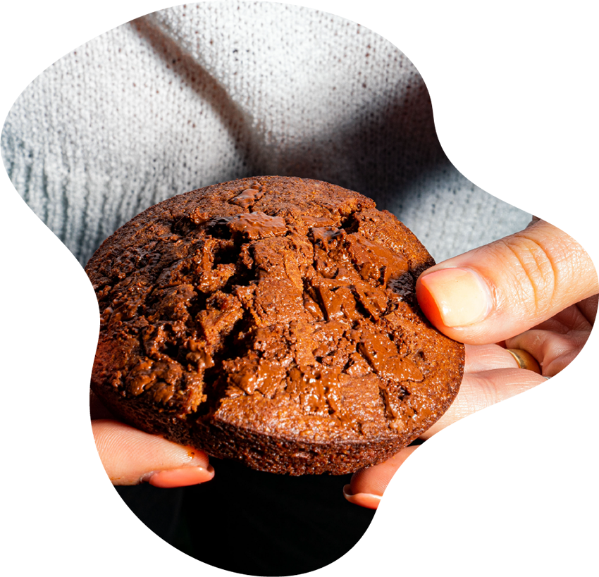 Hands holding a rich, chocolate cannabis brownie with a gooey center, representing edible products available at Housing Works Cannabis Co. dispensary.