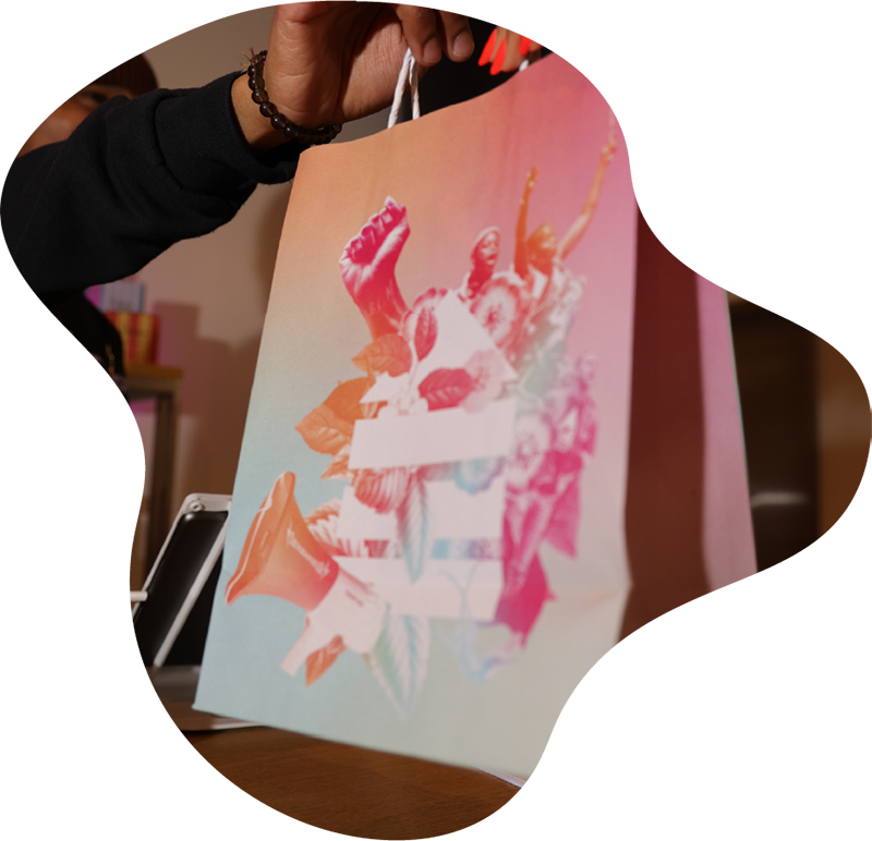 Customer holding a Housing Works Cannabis Co. shopping bag featuring vibrant protest-themed artwork and floral design.