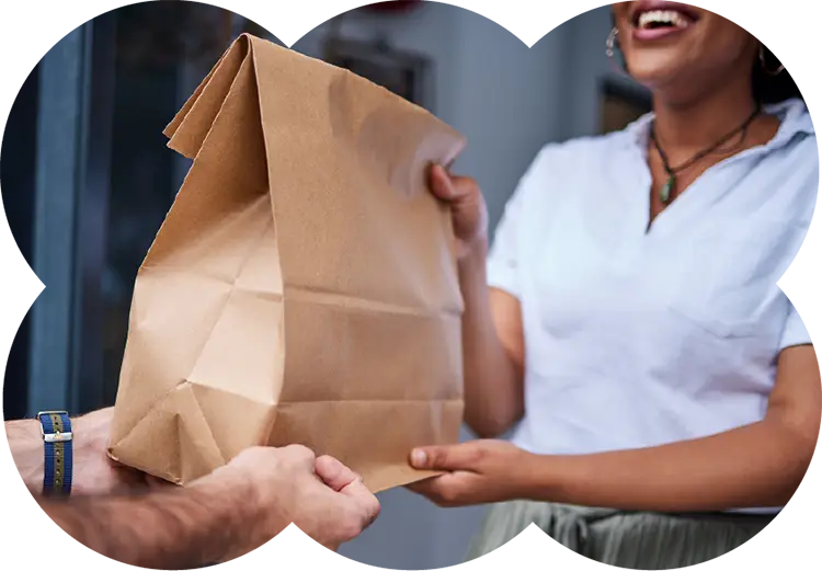 Smiling customer receiving a paper bag at their doorstep, representing Housing Works cannabis delivery service experience.