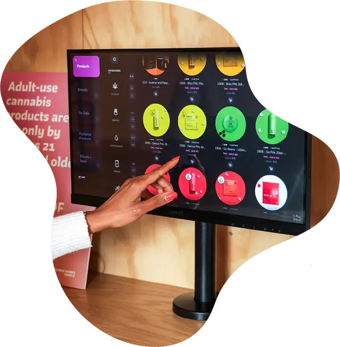 Customer browsing cannabis products on a touchscreen menu inside Housing Works Cannabis Co. dispensary.