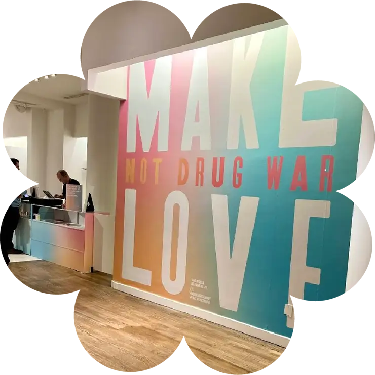 Interior wall at Housing Works Cannabis Co. with large text reading “Make Love Not Drug War” in gradient colors.
